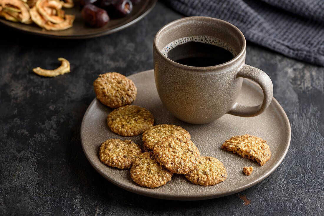 A cup of coffee on a plate with cereal cookies.