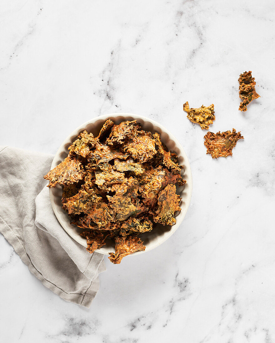 Bowl of kale chips on marble background