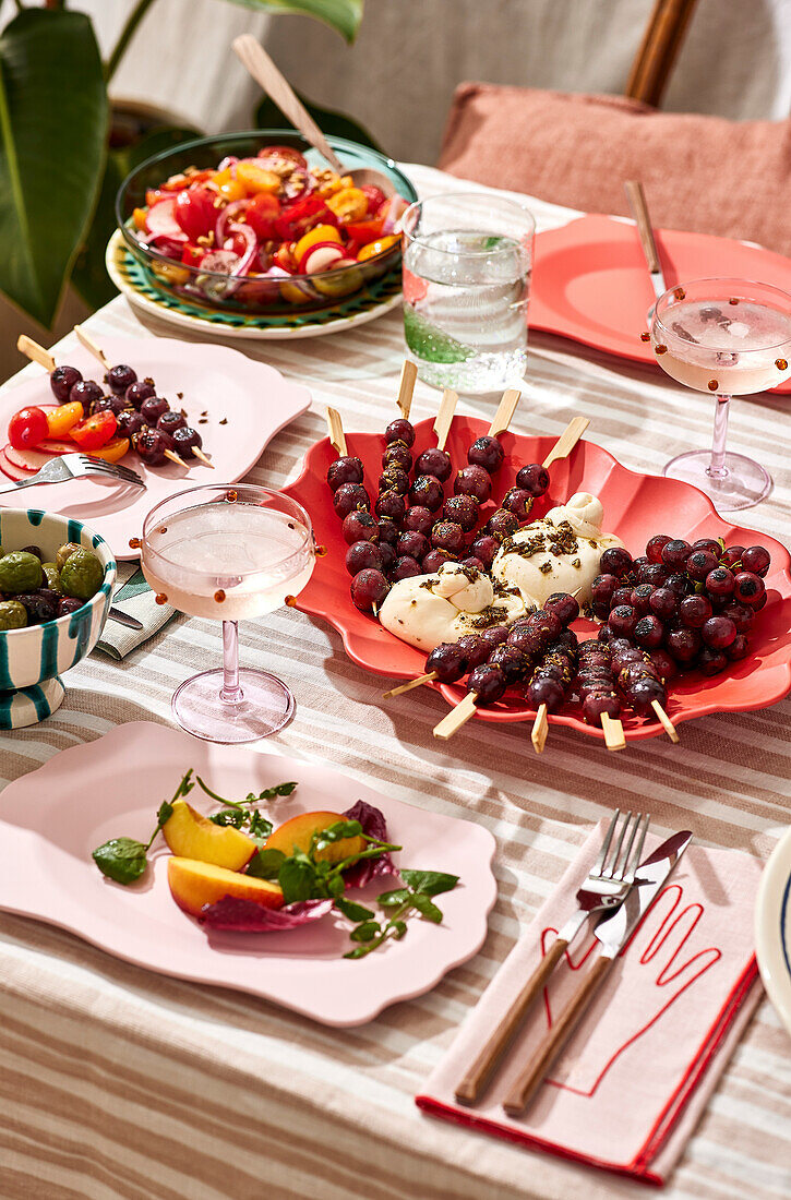 A picnic with salad at an outdoor table, with fresh fruit and fried food, on a striped tablecloth