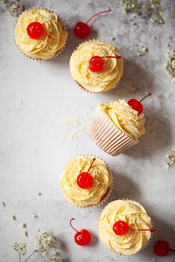 White chocolate cupcakes with piped white chocolate buttercream, grated white chocolate and maraschino cerries.