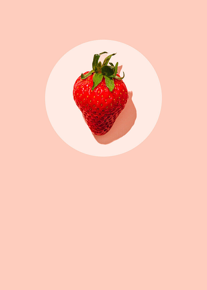 Single strawberry on a pink background