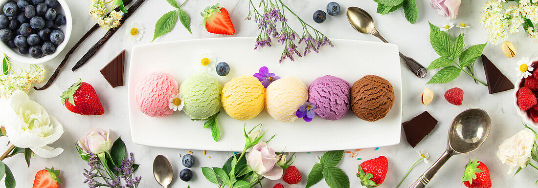 Set of various ice cream scoops and berries on white marble background. Strawberry, pistachio, mango, vanilla, blueberry and chocolate ice cream. Top view, flat lay, banner