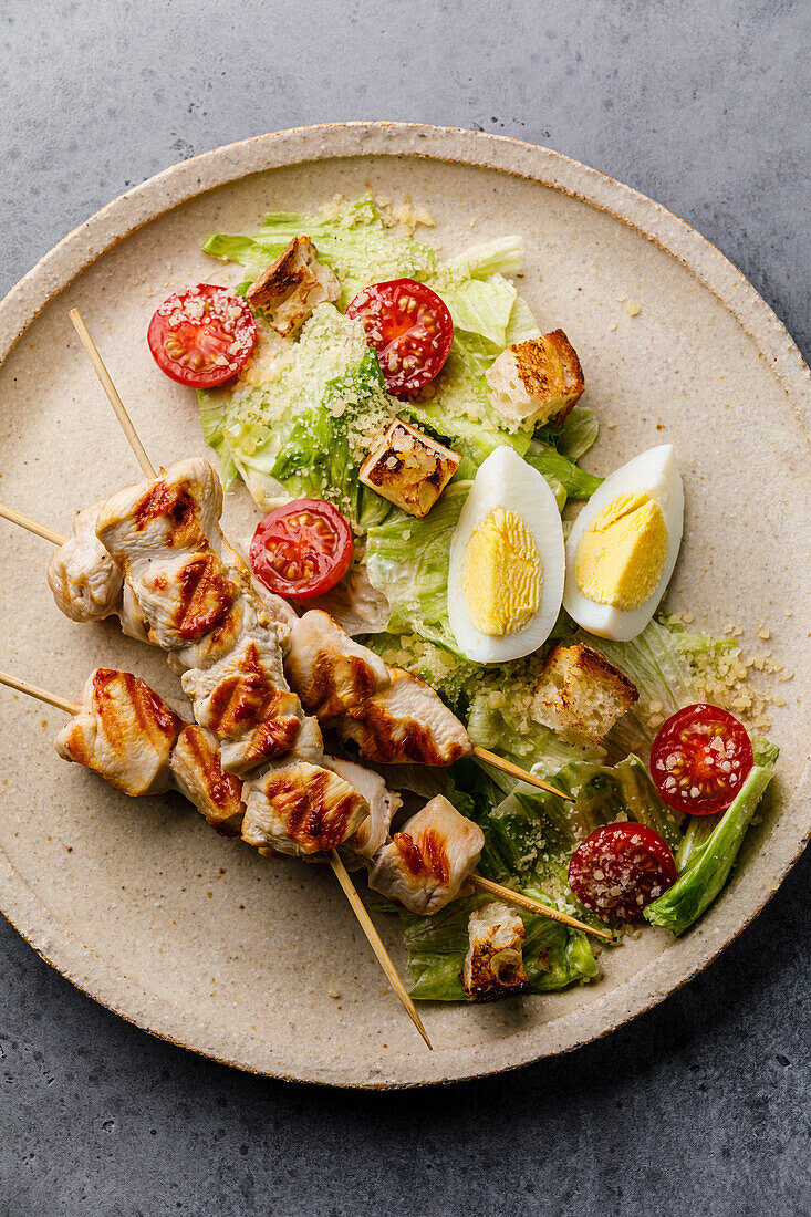 Caesar salad with Chicken breast meat on skewers and Egg on plate