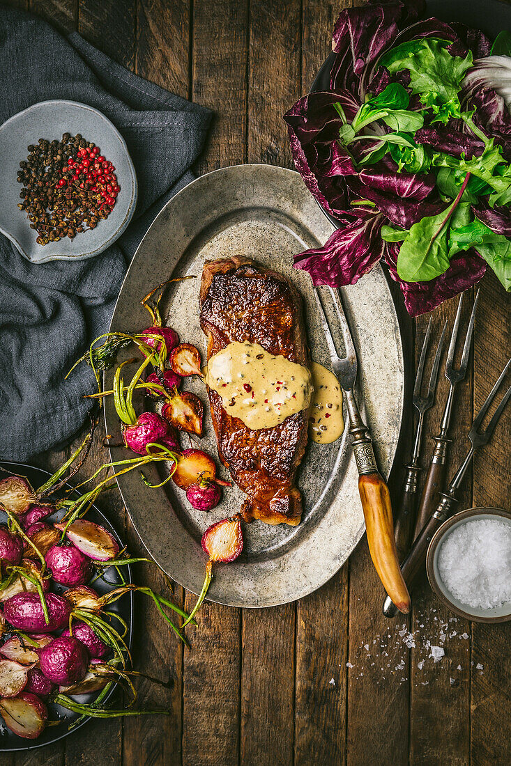 Steak au poivre mit Sahnesoße und gerösteten Radieschen auf Metallteller