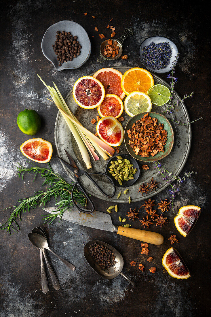 Flat lay arrangement of colorful citrus slices, lemongrass, herbs and spices on dark background. Ingredients for homemade tonic water for cocktails