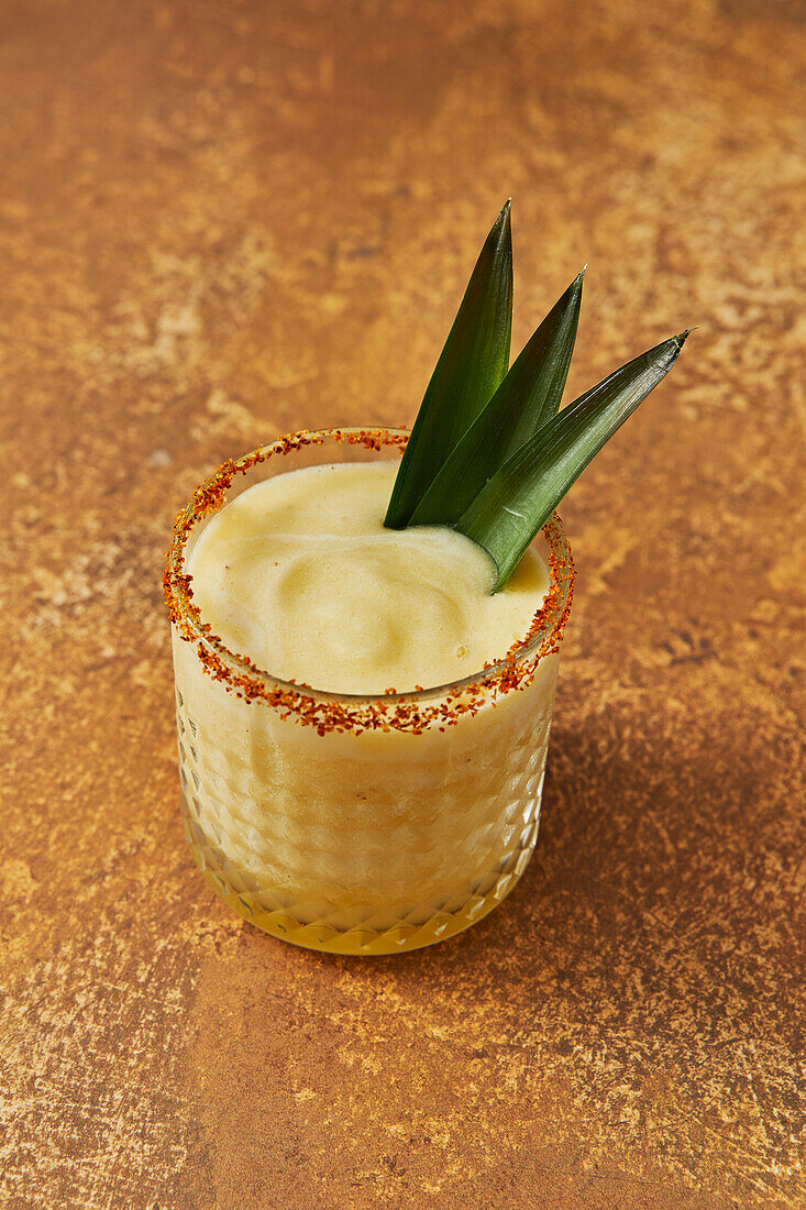 Pineapple Mocktail with Leaf Garnish on Gold Background