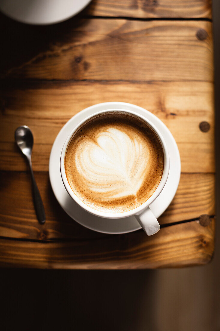 Kaffee in weißer Tasse auf Holztisch, mit Löffel