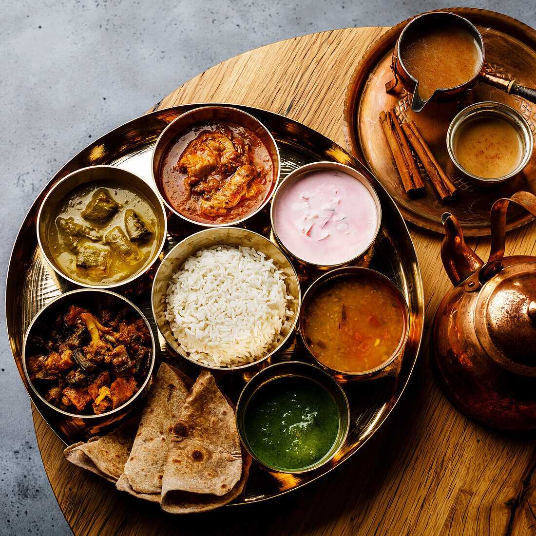 Indisches Essen Thali Gericht nach indischer Art mit Hühnerfleisch und Masala Tee Chai auf Holztisch