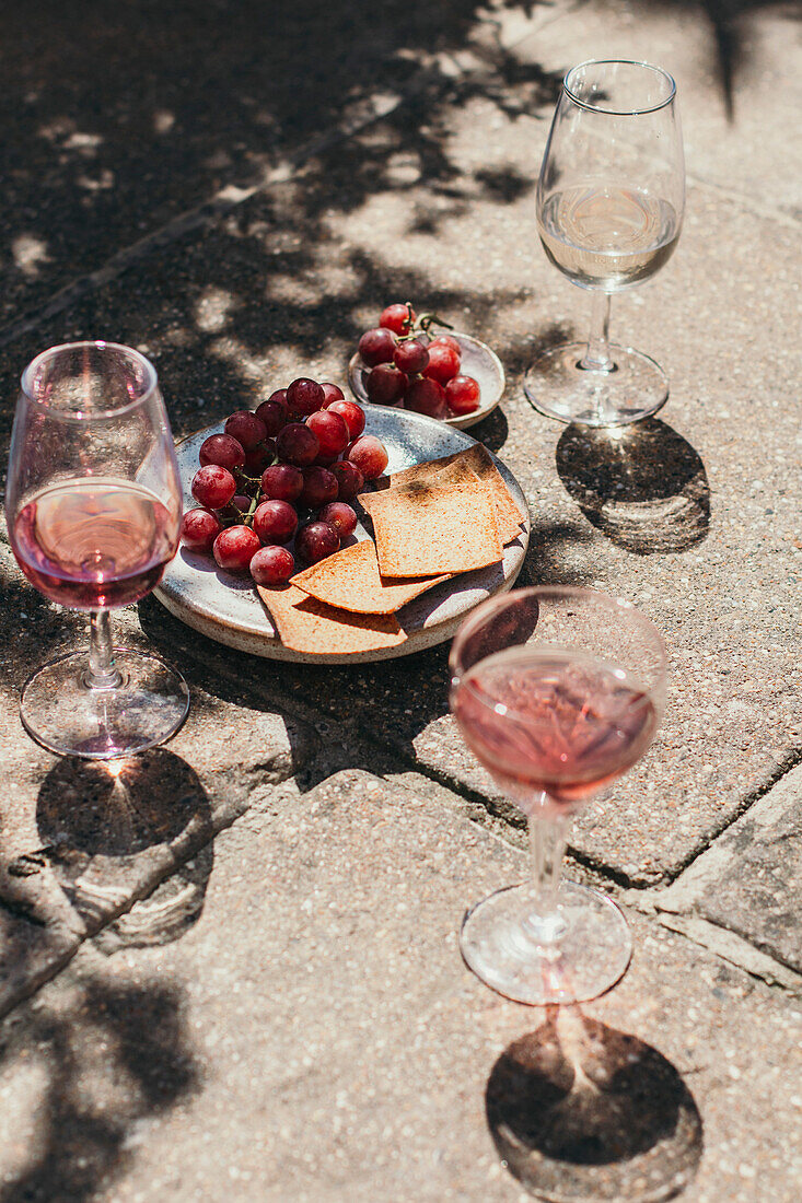 Glasses with pink wine and grapes in the background