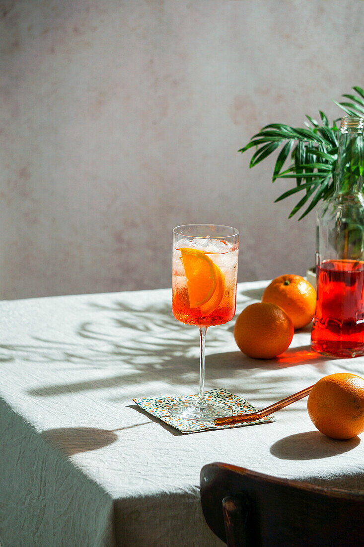 Aperol Spritz, cocktail, on a linen tablecloth, shade, harsh sunlight, summer drink in a glass