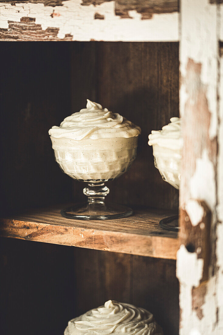 Vanilla mousse dessert served in a glass on a rustic wooden board