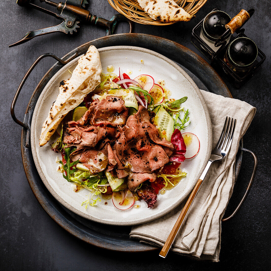 Salad with roast beef and vegetables on a dark background