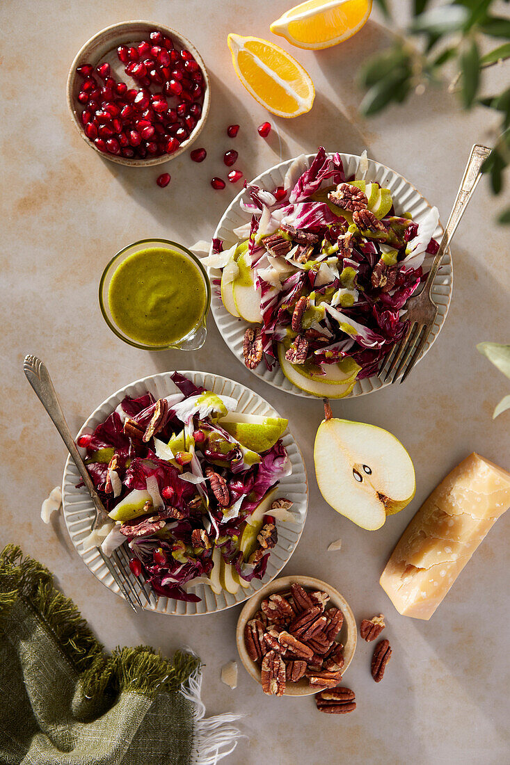 Radicchio-Salat mit Birnen, Pekannüssen, Granatapfel, Pekannüssen und Basilikum-Vinaigrette auf neutralem braunen Hintergrund mit grünem Tuch