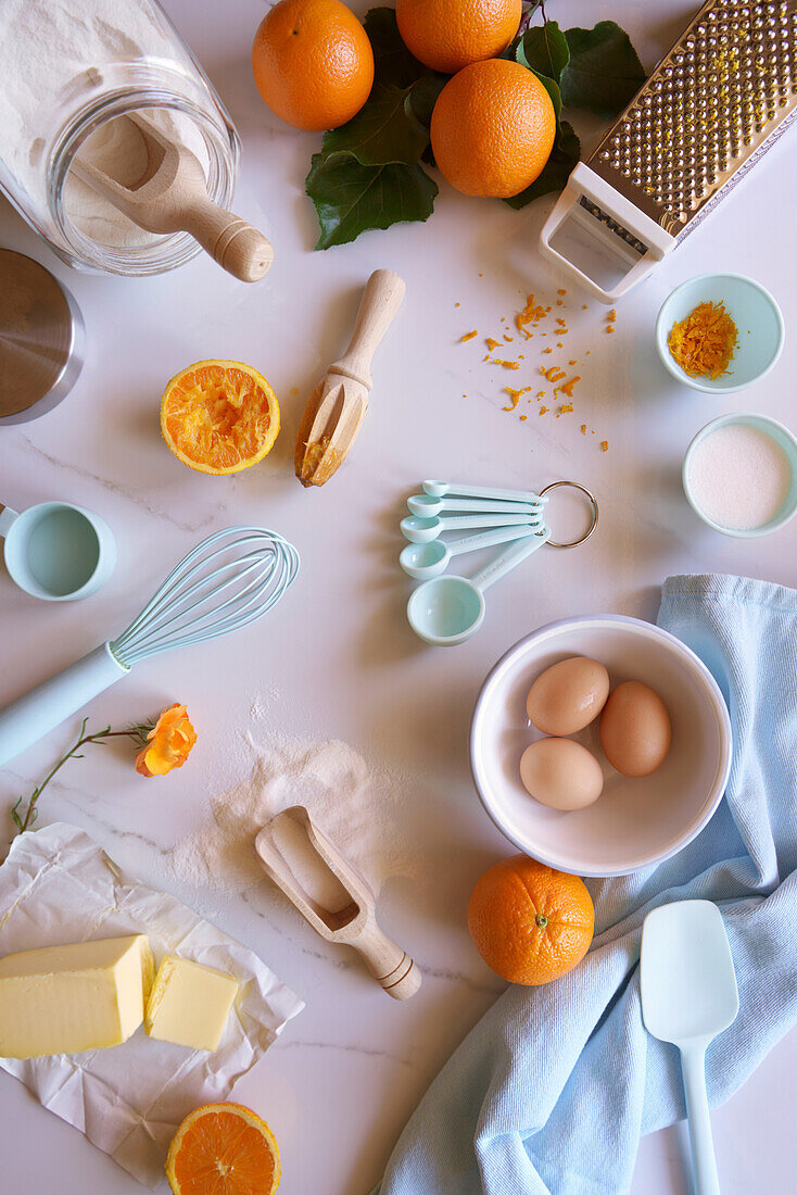 Backvorbereitung mit Zutaten für Orangen-Madeira-Kuchen auf weißer Marmorplatte