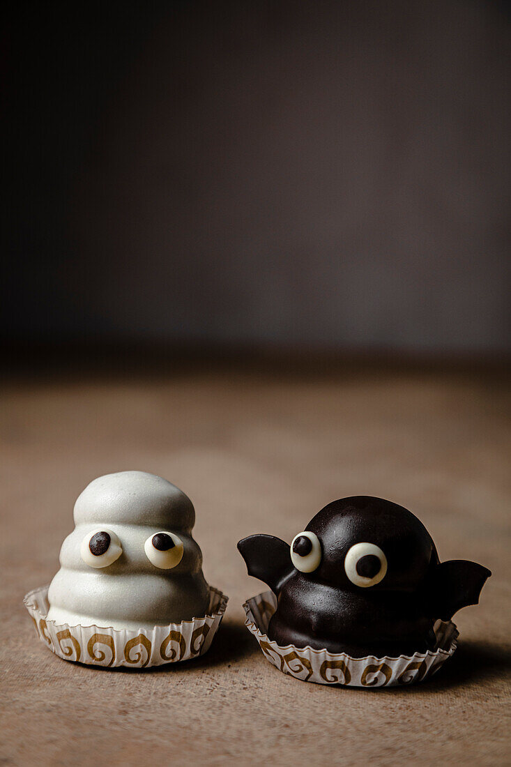 Ghost and bat sweets over table for Halloween; made with cookie base, dulce de leche fill and chocolate coating