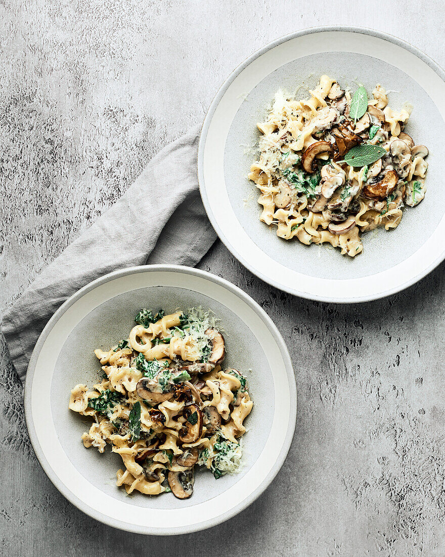 Two bowls of vegan mushroom cream noodle on a grey background