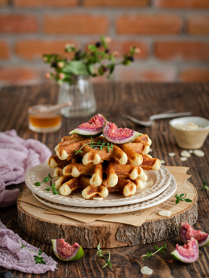 A stack of waffles with figs, thyme and honey on a rustic wooden board