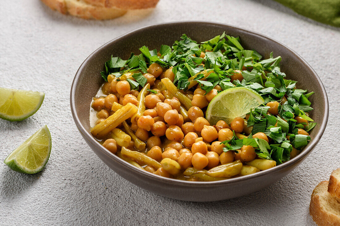 The dish of chickpeas and asparagus beans is flavoured with a slice of lime and chopped parsley. Close-up