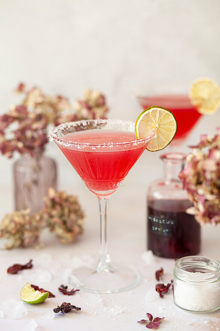 Ein Hibiskus-Margarita-Cocktail in einem Martini-Glas, mit Salz bestreut und mit Limette garniert