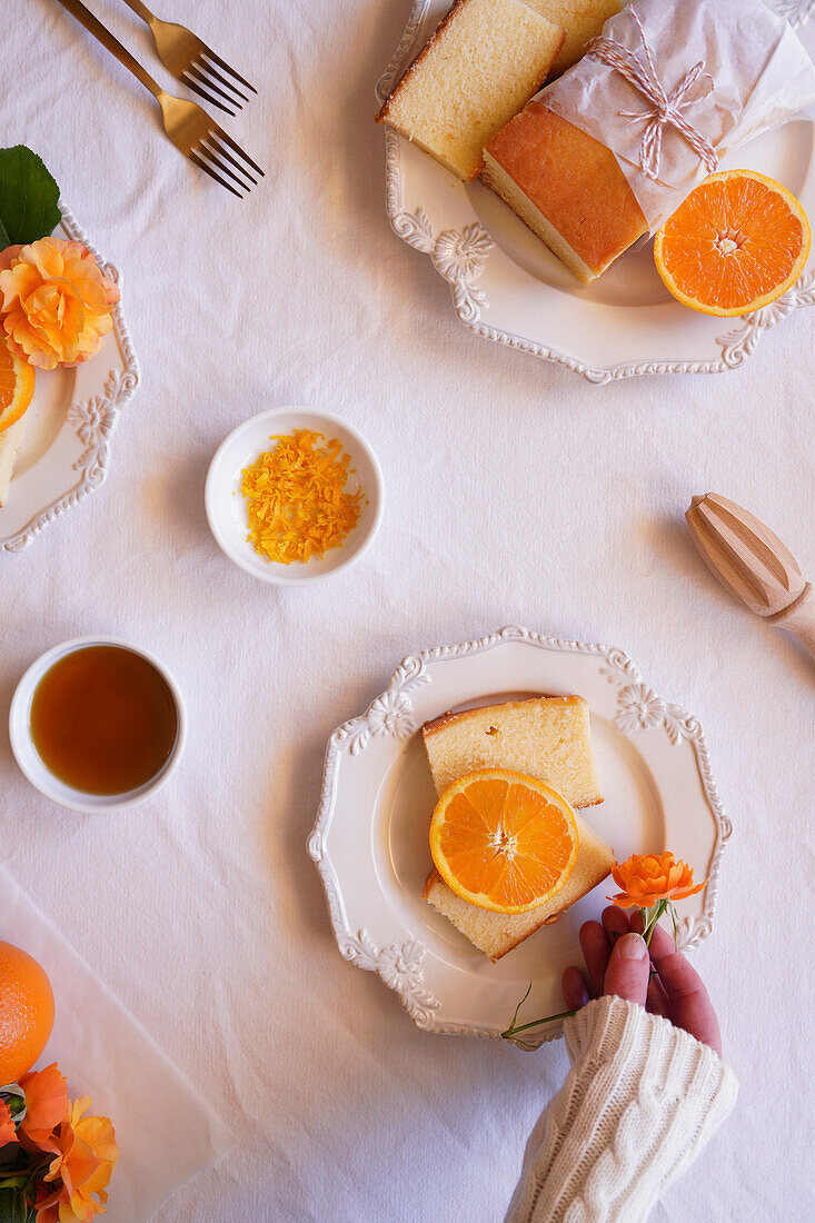 Orangen-Madeira-Kuchen mit Sirup und Orangenschalen. Tischdekoration für den Nachmittagstee Flatlay