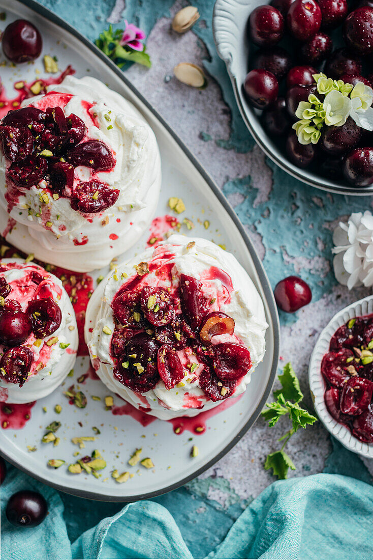 Meringues mit frischer Sahne und reifen Kirschen auf blauem Hintergrund