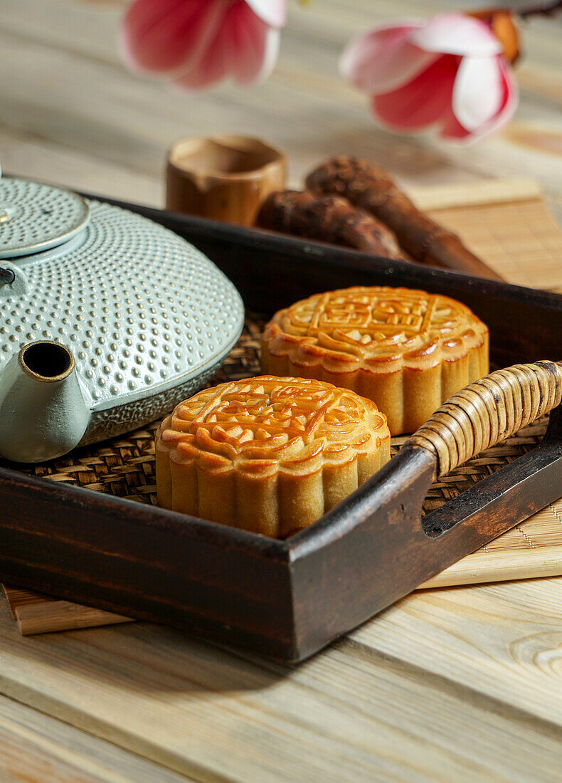 Mondkuchen zum Mittherbstfest, Konzept für traditionelles chinesisches Festessen auf einem asiatischen Holztablett mit Teekanne