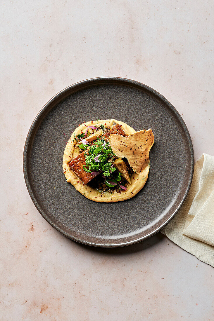 Slow-cooked lamb shoulder in spice crust, yellow fava puree, warm artichoke, lentil and broad bean salad, delicate herbs, caraway wafer