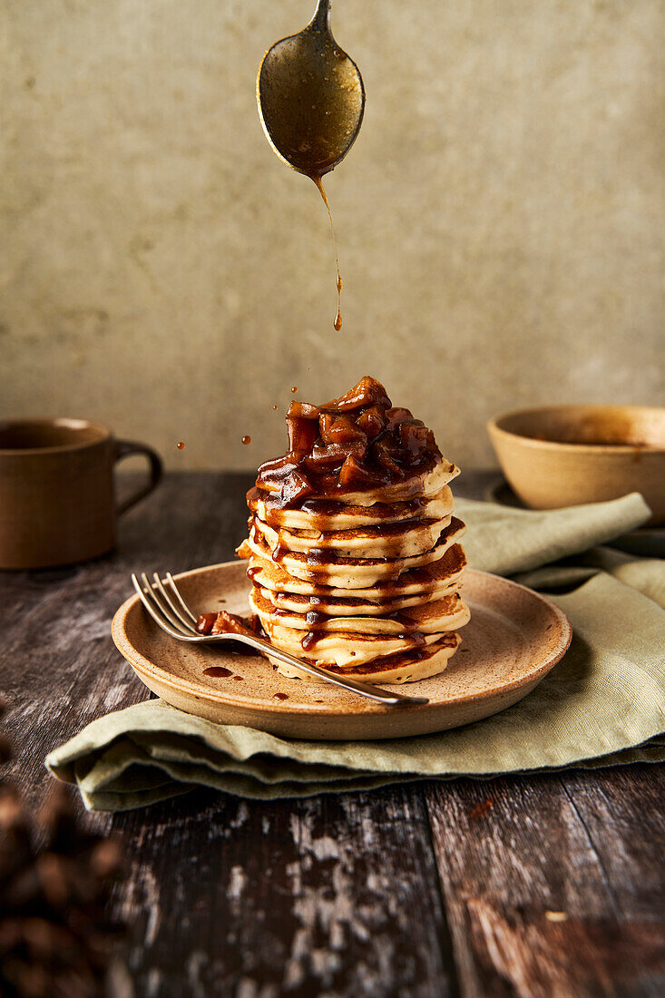 Apple and cinnamon pancake stack on a wooden surface and sage green background
