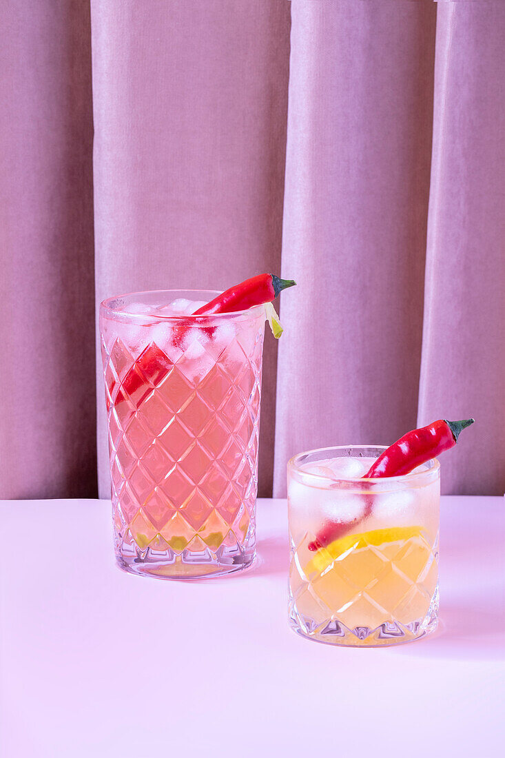 Clear glasses of refreshing cold cocktails served with pepper and ice cubes on the table