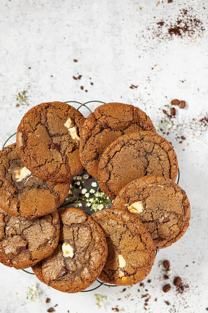Chocolate chip espresso cookies arranged in a circle on a wire rack with ground coffee scattered around the worktop.