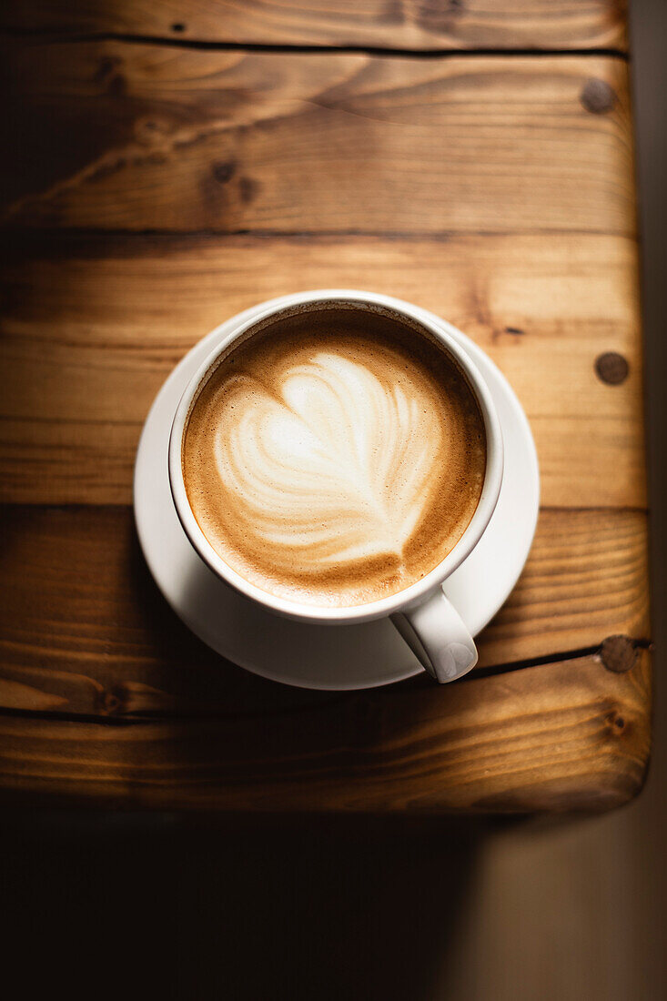 Kaffee in weißer Tasse auf Holztisch, mit Löffel