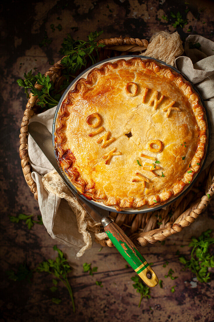 A sausage pie made from shortcrust pastry, decorated with puff pastry letters meaning "oink oink oink"