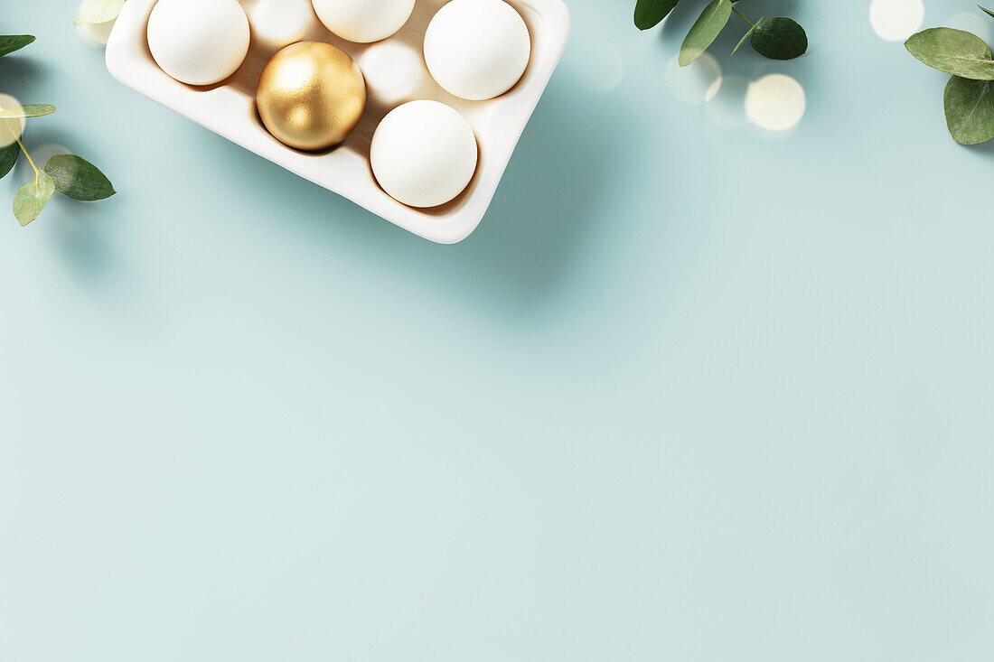 Easter table decoration. Cheerful Easter concept with golden table setting, Easter eggs, feathers and spring flowers. Easter background with copy space. Flat lay