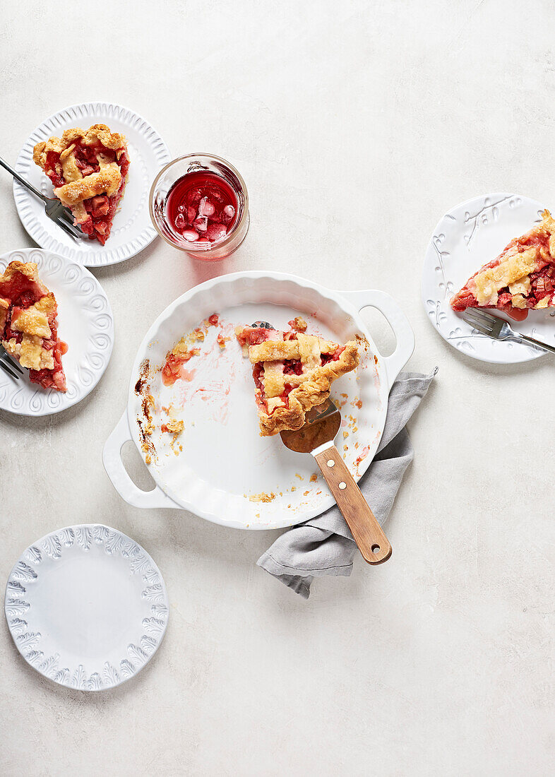 Vier Scheiben veganer Erdbeer-Rhabarber-Kuchen mit rosa Getränk