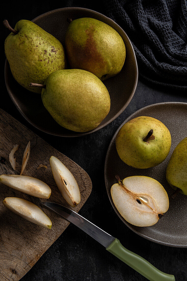 Pears on plates. Slices of pear and a knife on the chopping board. View from above