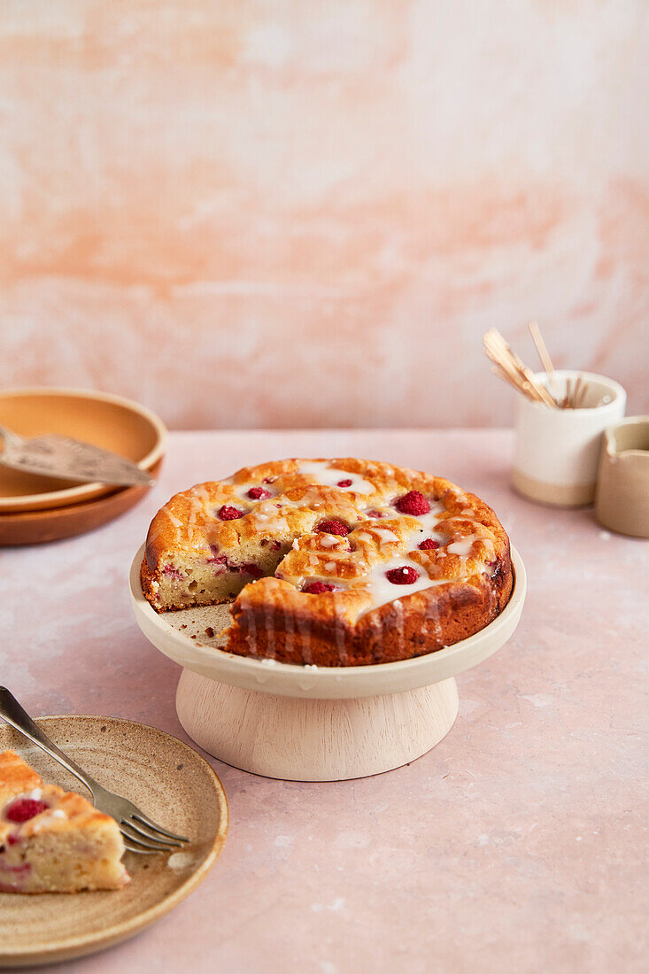 Raspberry ricotta cake with icing on a stand with slices