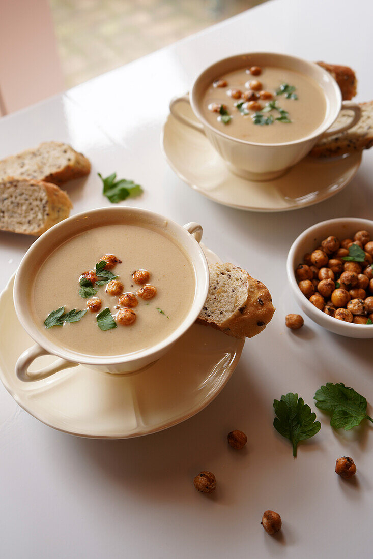 Vegan soup of cauliflower, cumin and lima beans on a white marble table, close-up