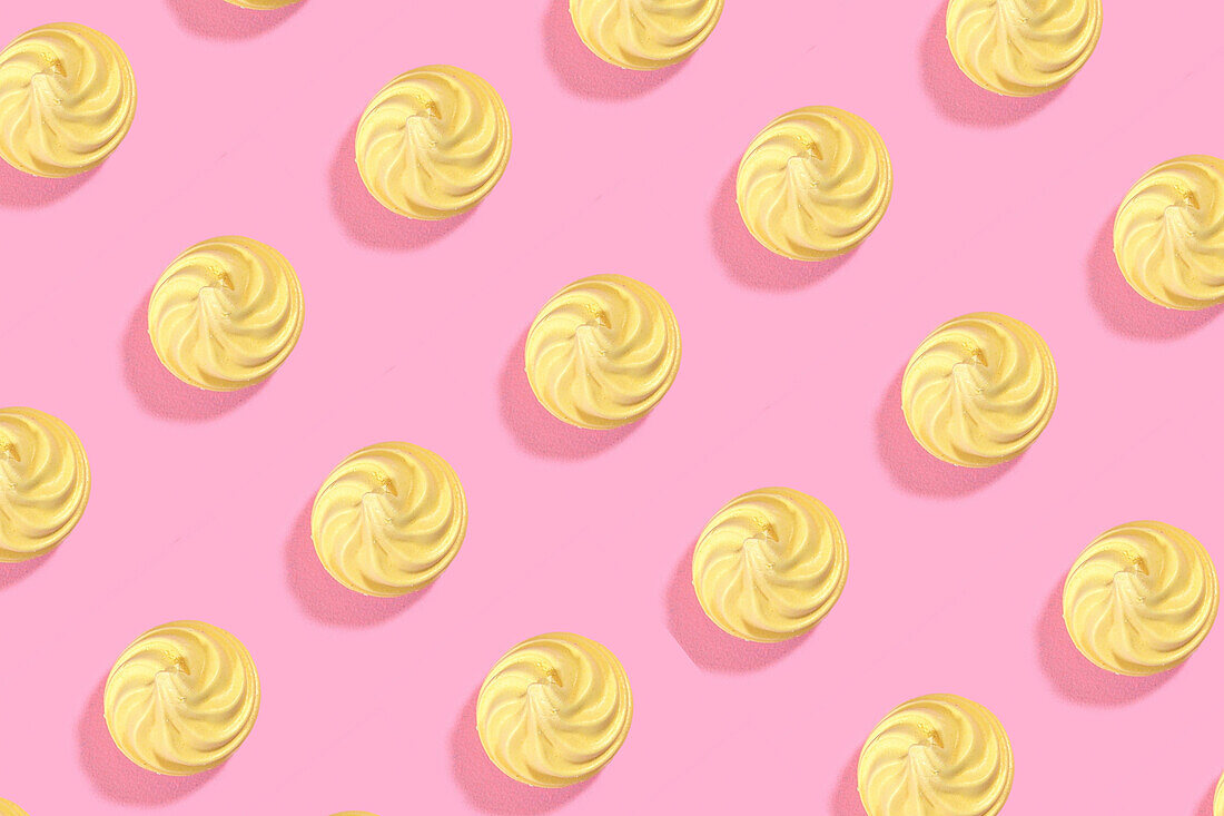 Modern retro color theme pattern of yellow meringues against a pink background.