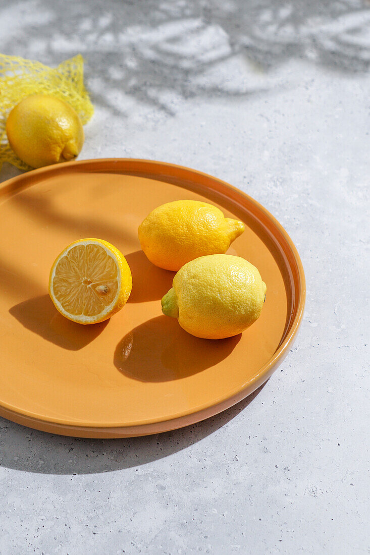 Fresh lemons on a yellow plate. harsh sunlight and shade