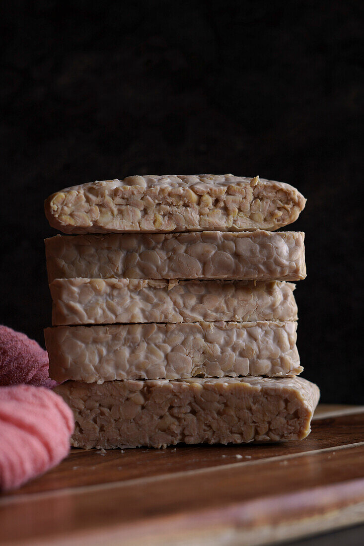 Slices of Indonesian style fermented tempeh against a dark background.