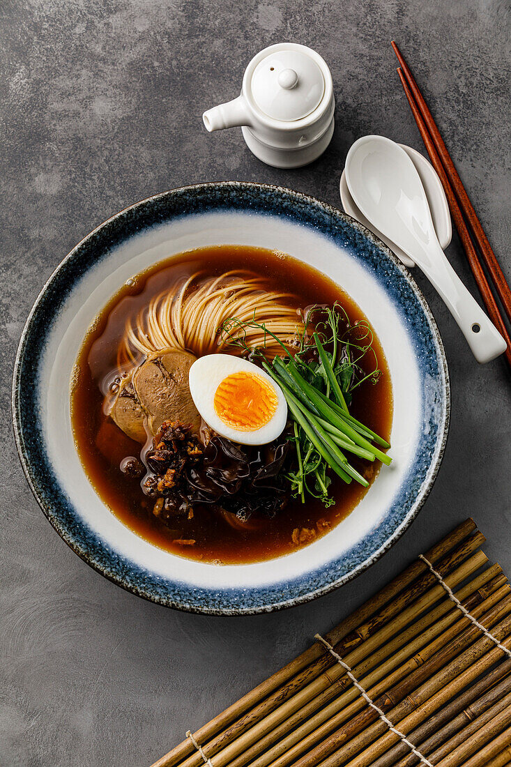 Ramen, Asian noodles in broth with beef tongue, mushrooms and eggs in a bowl
