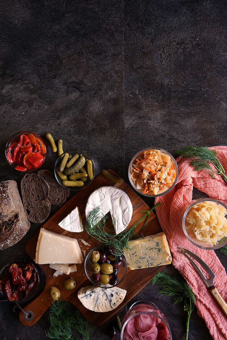 Gesunde probiotische Käseplatte mit Kimchi, dunkel gefärbtem Sauerteigbrot und fermentiertem Gemüse, mit negativem Kopierraum