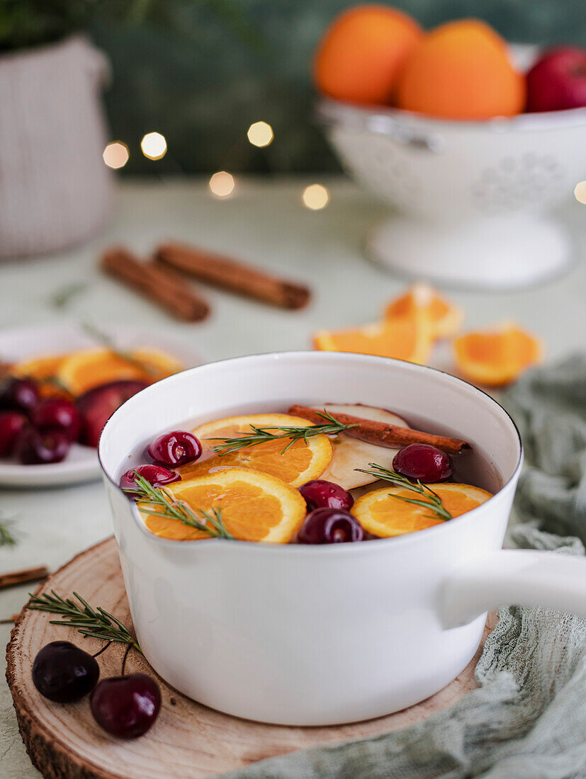 Christmas punch with cherries, oranges and rosemary, in a white pot