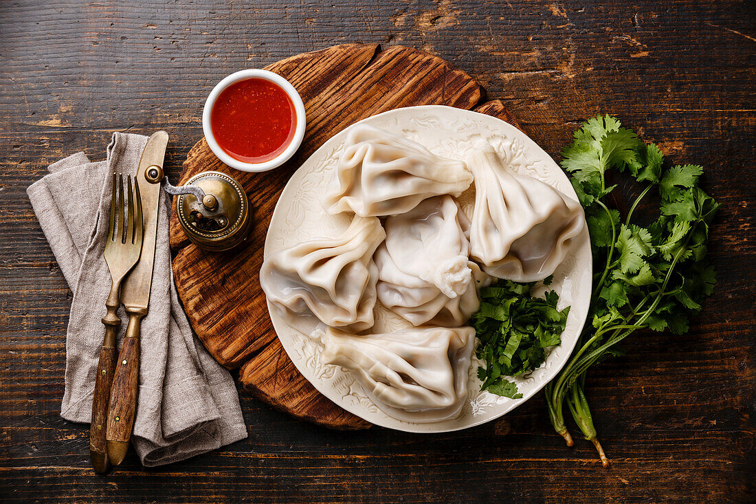 Georgian dumplings khinkali with meat and spicy tomato sauce satsebeli on a wooden background