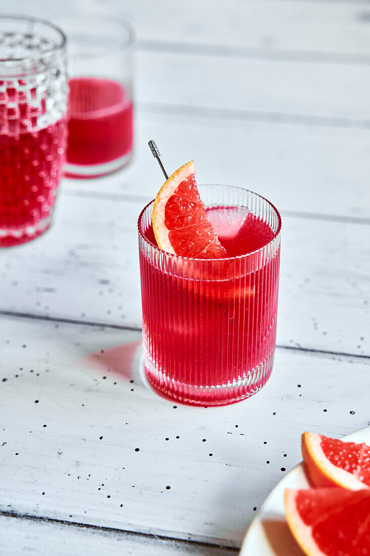 Hisbiscus grapegruit iced tea with grapefruit slice on white wood surface