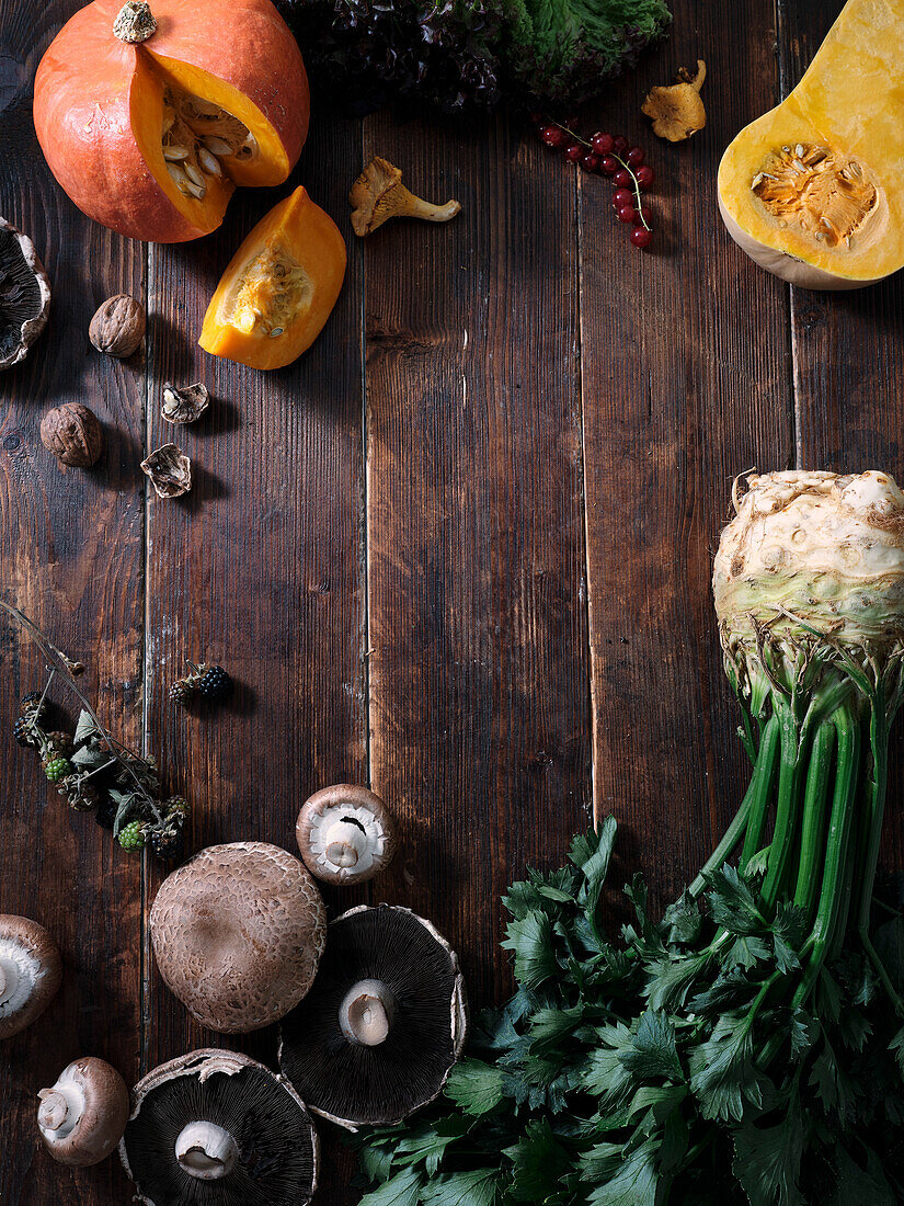 Herbstliche Lebensmittelzutaten auf dunklem Holzhintergrund mit Textfeld. Flachlage mit Herbstgemüse, Beeren und Pilzen vom lokalen Markt. Vegane Zutaten