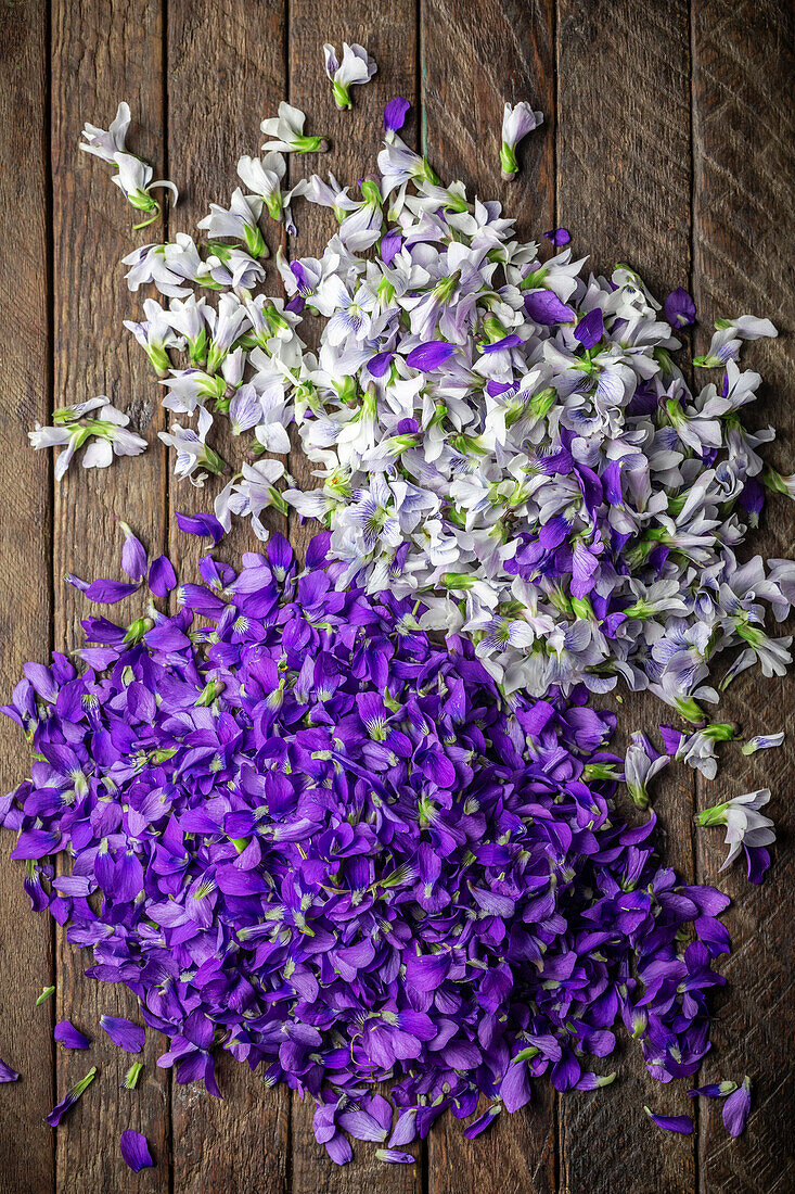 Purple and white violet petals arranged on a wooden table