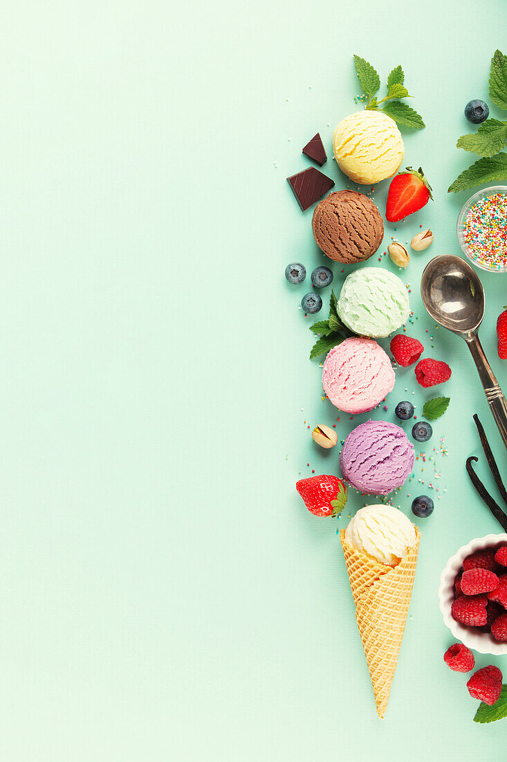 Flying scoops of ice cream and ingredients on a pastel-coloured light blue background. Summery minimal concept