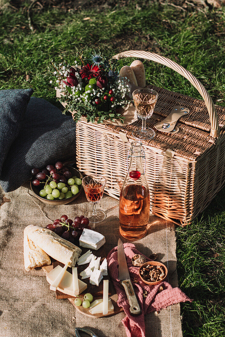 Winter picnic scene with basket, flowers, grapes and cheese