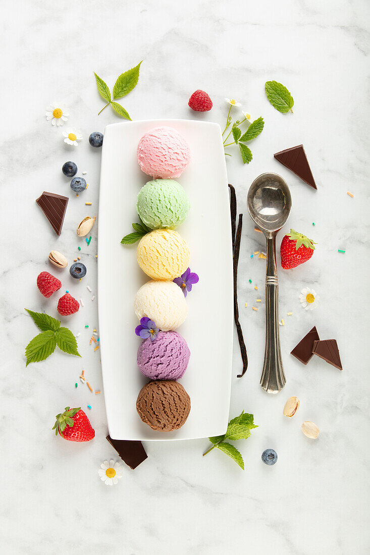 Set of various ice cream scoops and berries on white marble background. Strawberry, pistachio, mango, vanilla, blueberry and chocolate ice cream. Top view, flat lay